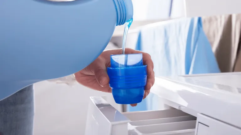 Blue laundry detergent poured into a measuring cup